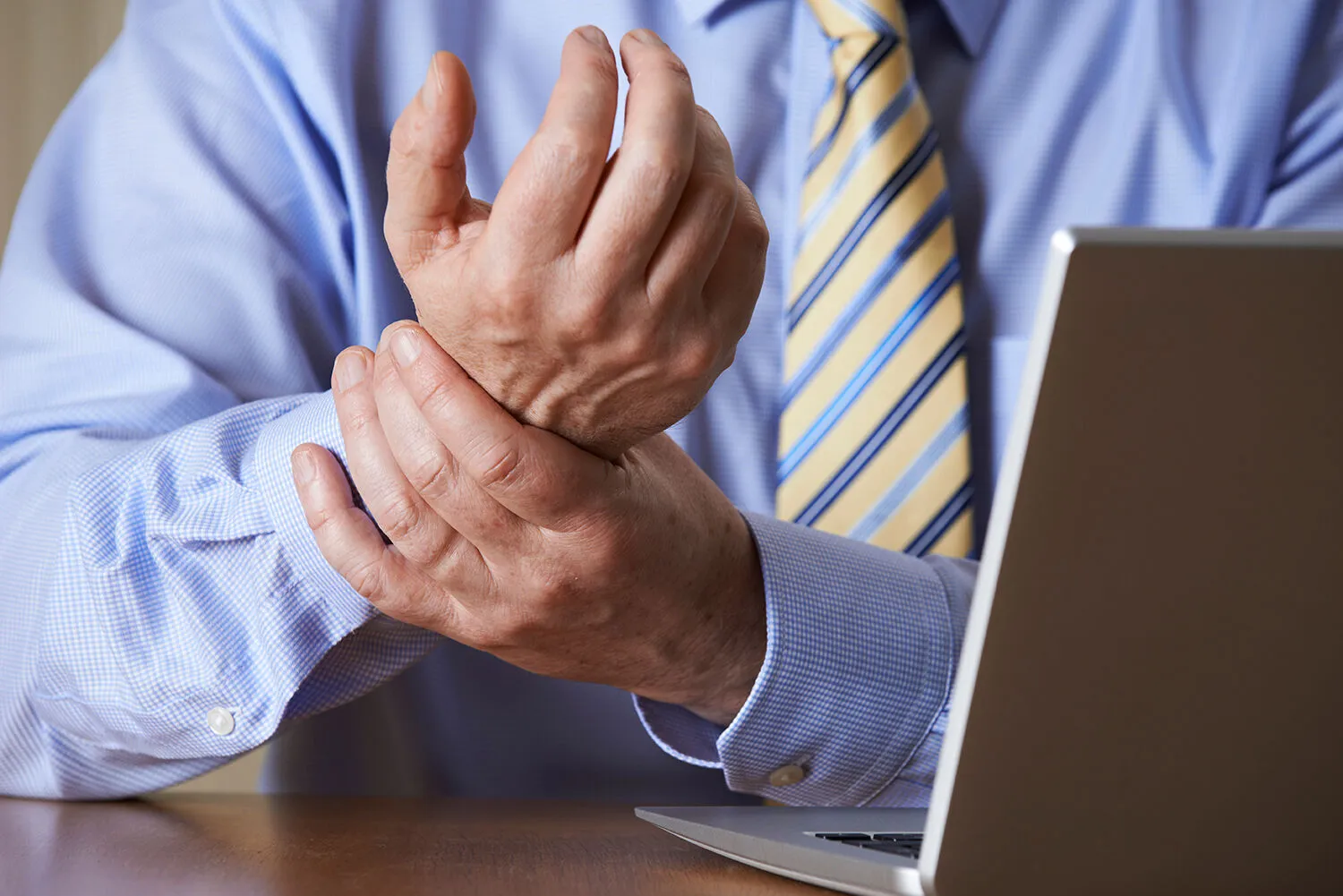 man having a wrist pain while working on his laptop