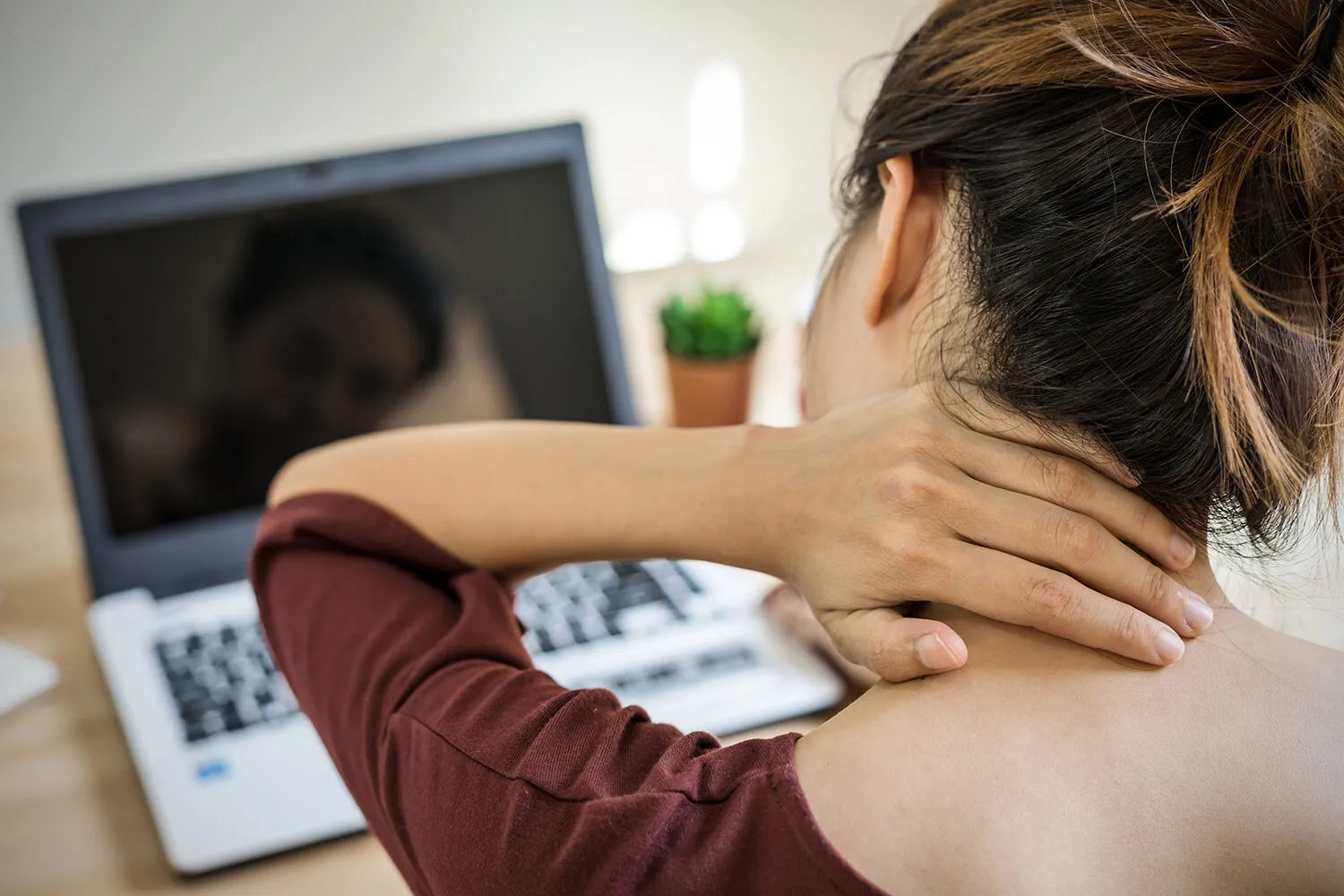 woman having a neck pain while working on her laptop